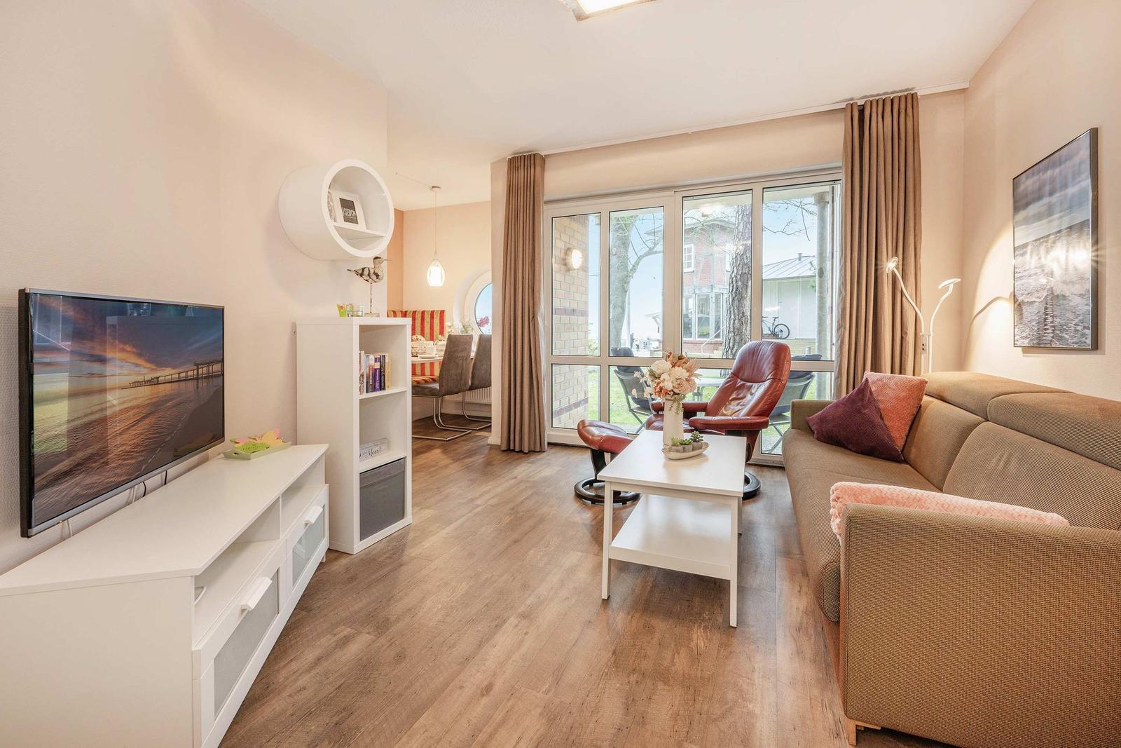 Wohnzimmer mit Sofa, Fernseher und Blick auf Garten