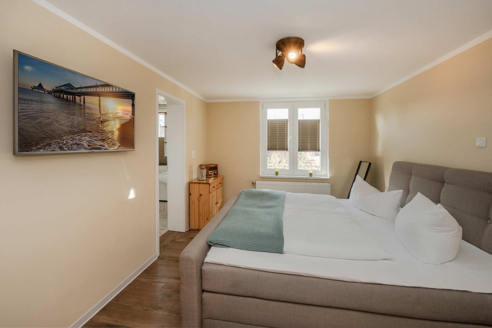 Schlafzimmer mit Bett, Fenster und Wandbild an der Wand.