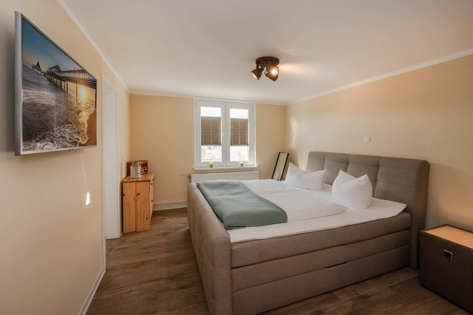 Schlafzimmer mit Bett, Fenster und Wandbild