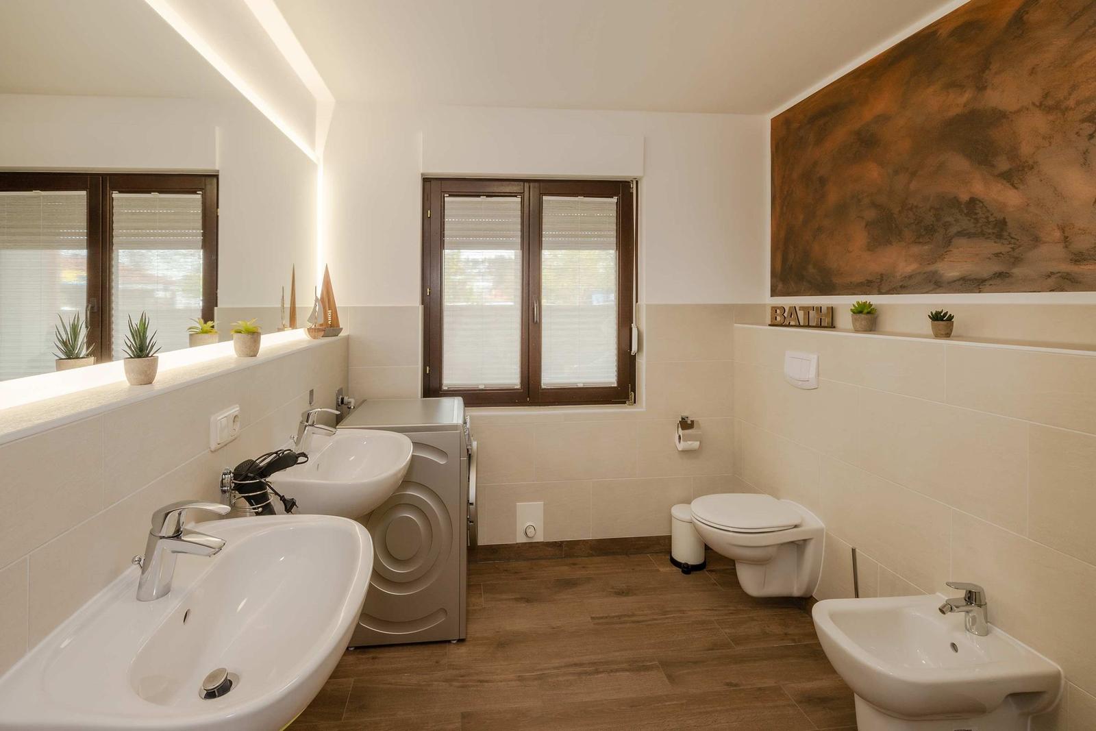 Bad mit zwei Waschbecken, Toilette, Waschmaschine und Fenster