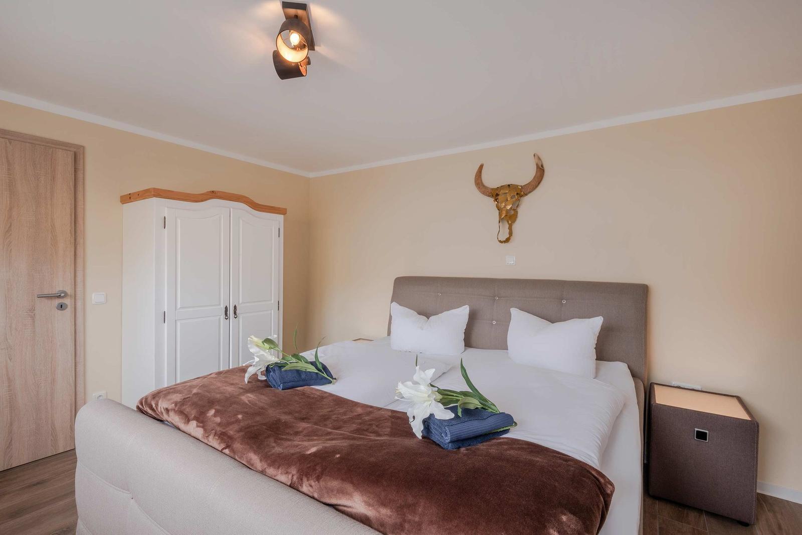 Schlafzimmer mit Bett, Kleiderschrank und Wanddekoration.