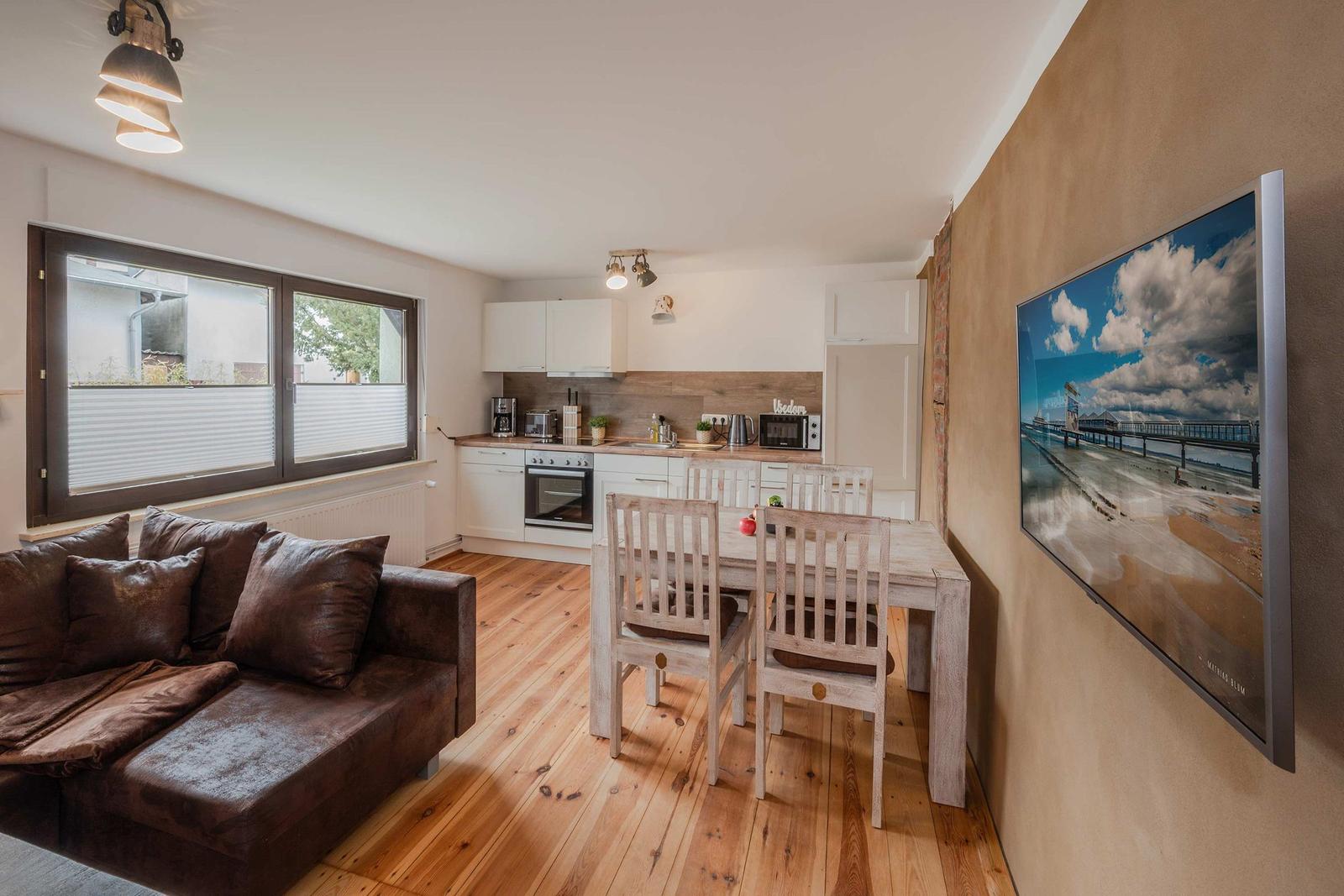 Wohnbereich mit Essbereich, Küche und Sofa. Holzboden und Wandbild.
