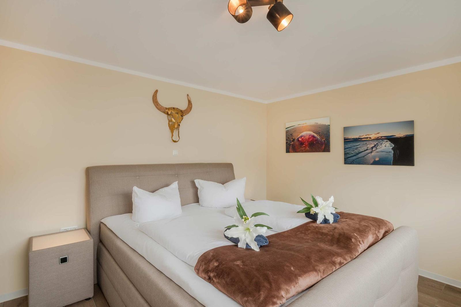 Schlafzimmer mit Bett, Nachttisch und Wanddekoration.