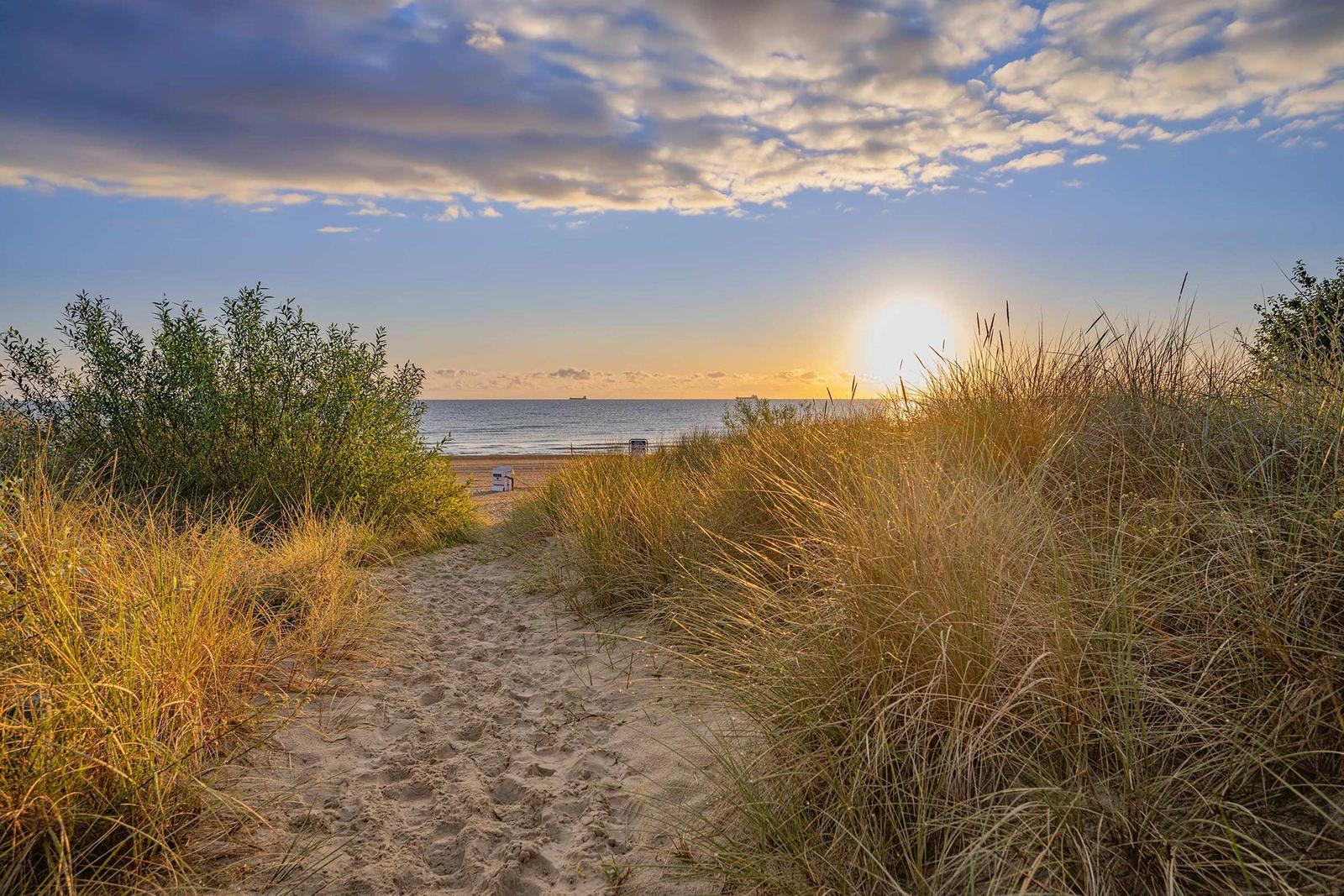 Sandweg durch Dünen zur Strandpromenade bei Sonnenuntergang