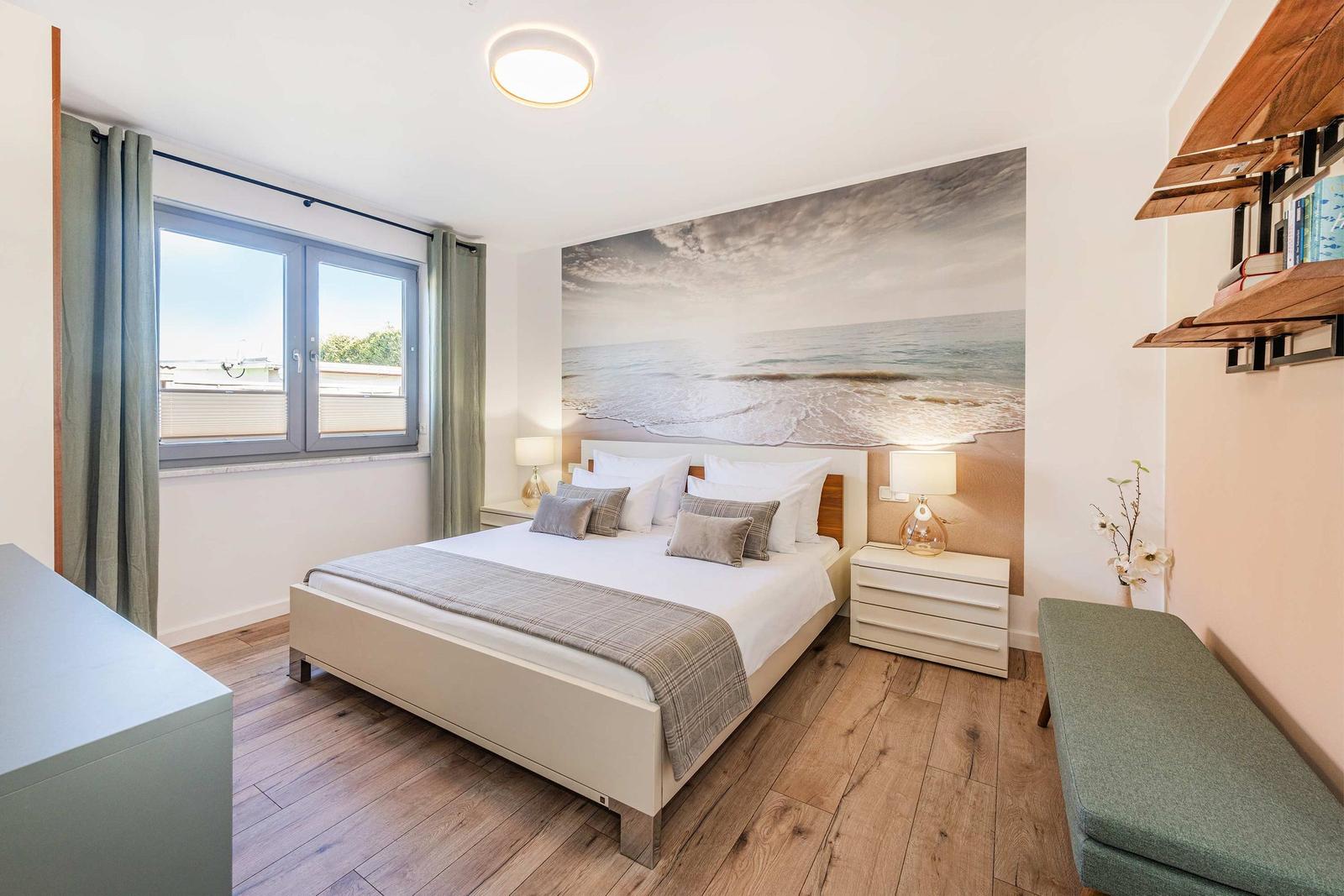 Schlafzimmer mit Bett, Fenster, Wandbild und Holzboden.