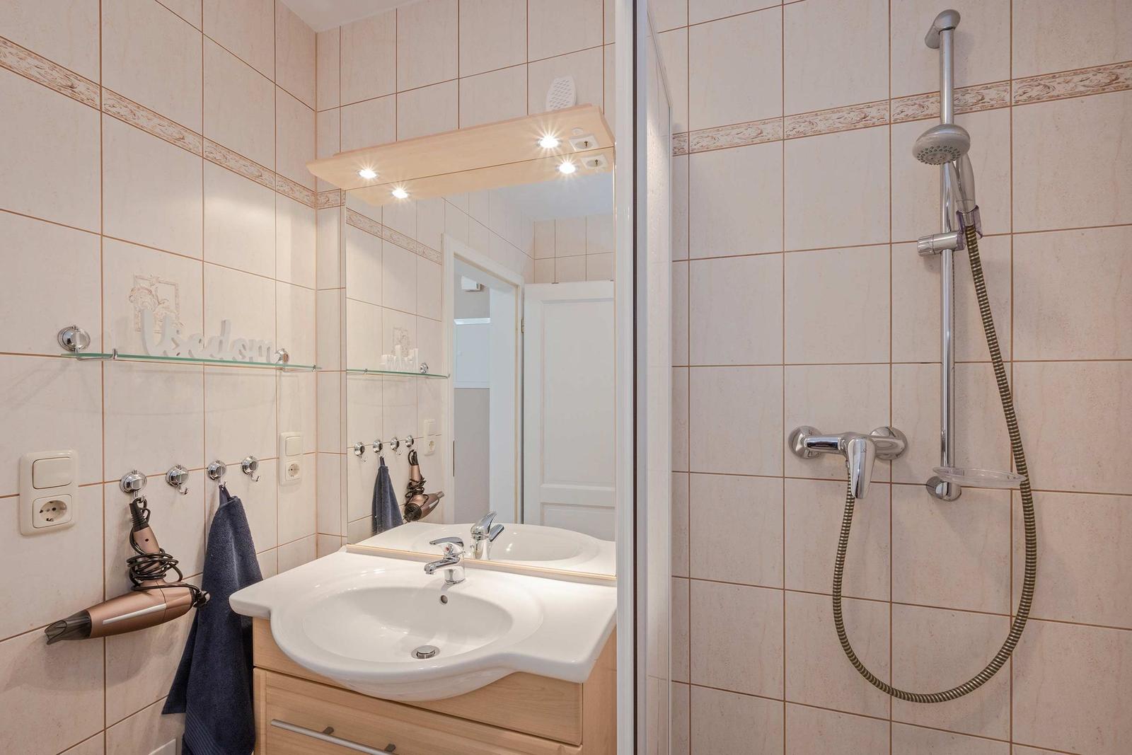 Bad mit Dusche, Waschbecken und Spiegel