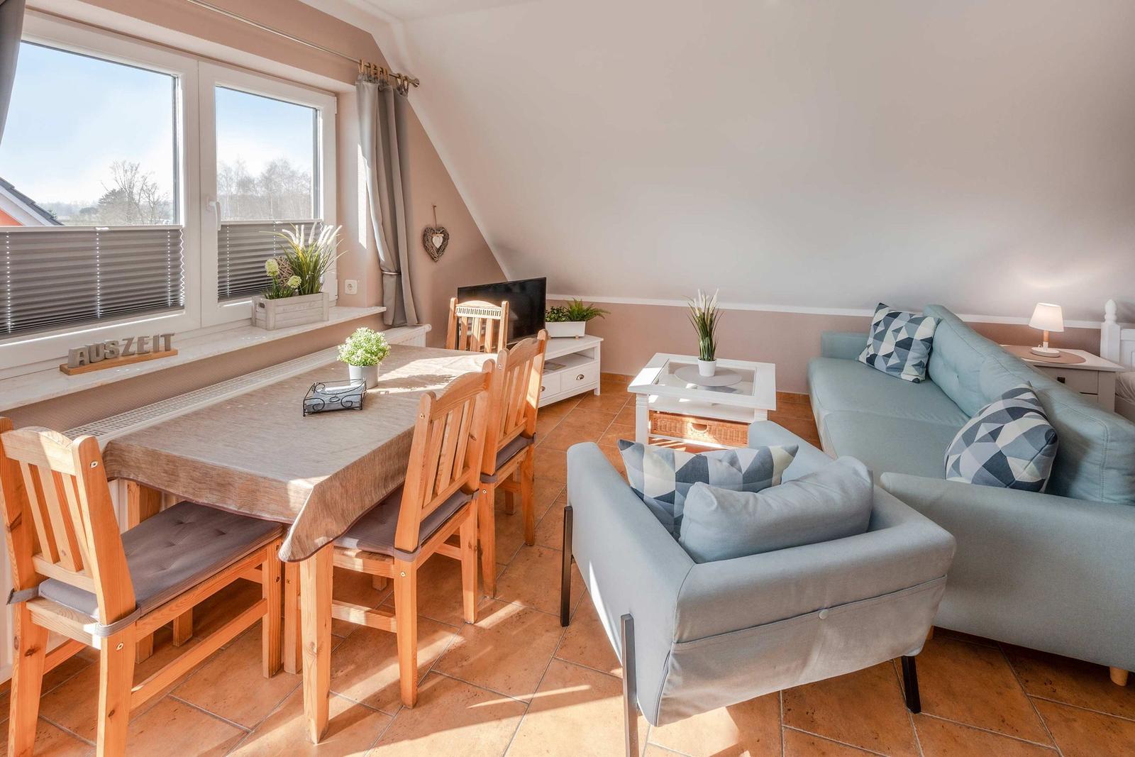 Wohn- und Essbereich mit Sofa, Sessel, Esstisch und Fenster.