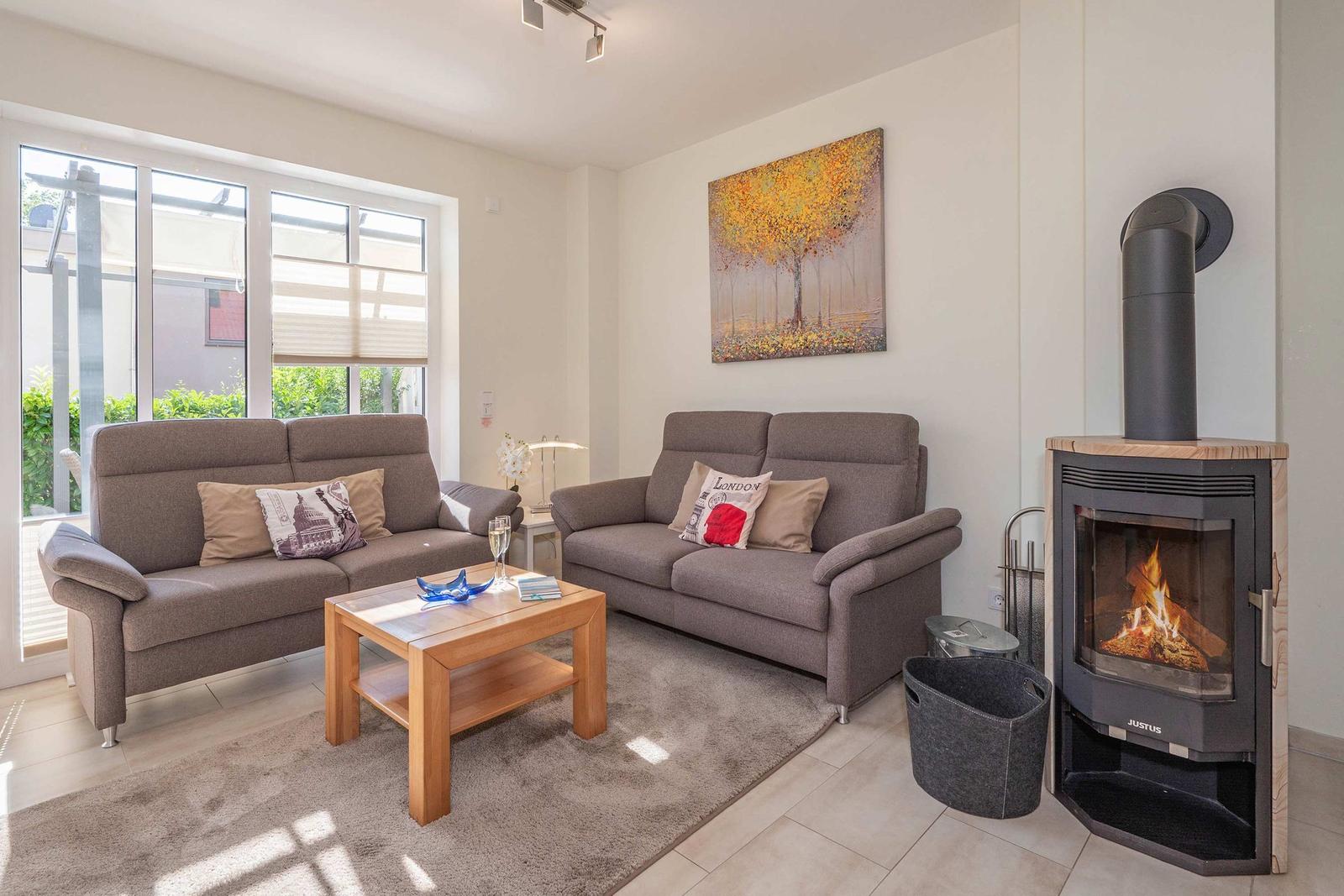 Wohnzimmer mit zwei Sofas, Kamin und großem Fenster. Holztisch und Wandbild.