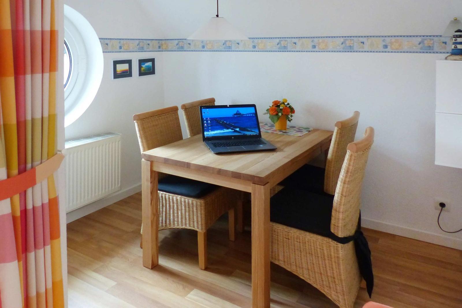 Esszimmer mit Holztisch, vier Stühlen und Laptop auf Tisch