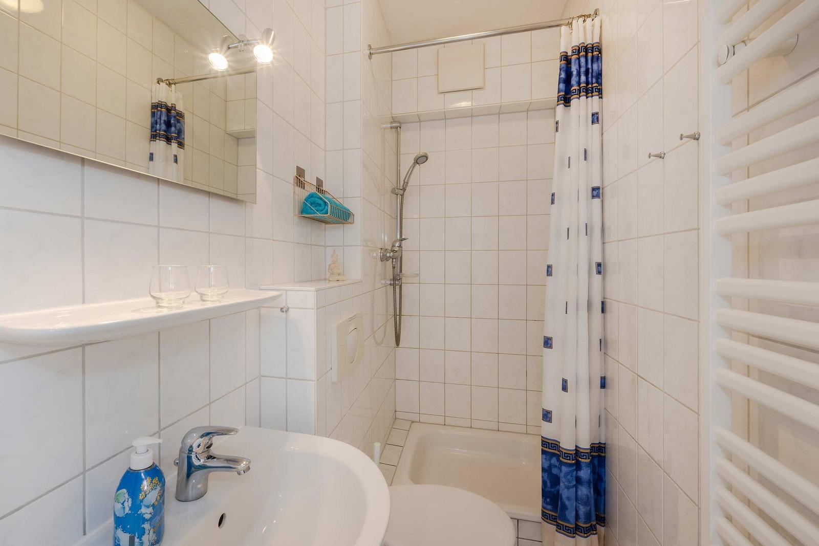 Badezimmer mit Dusche, Waschbecken und Heizung.