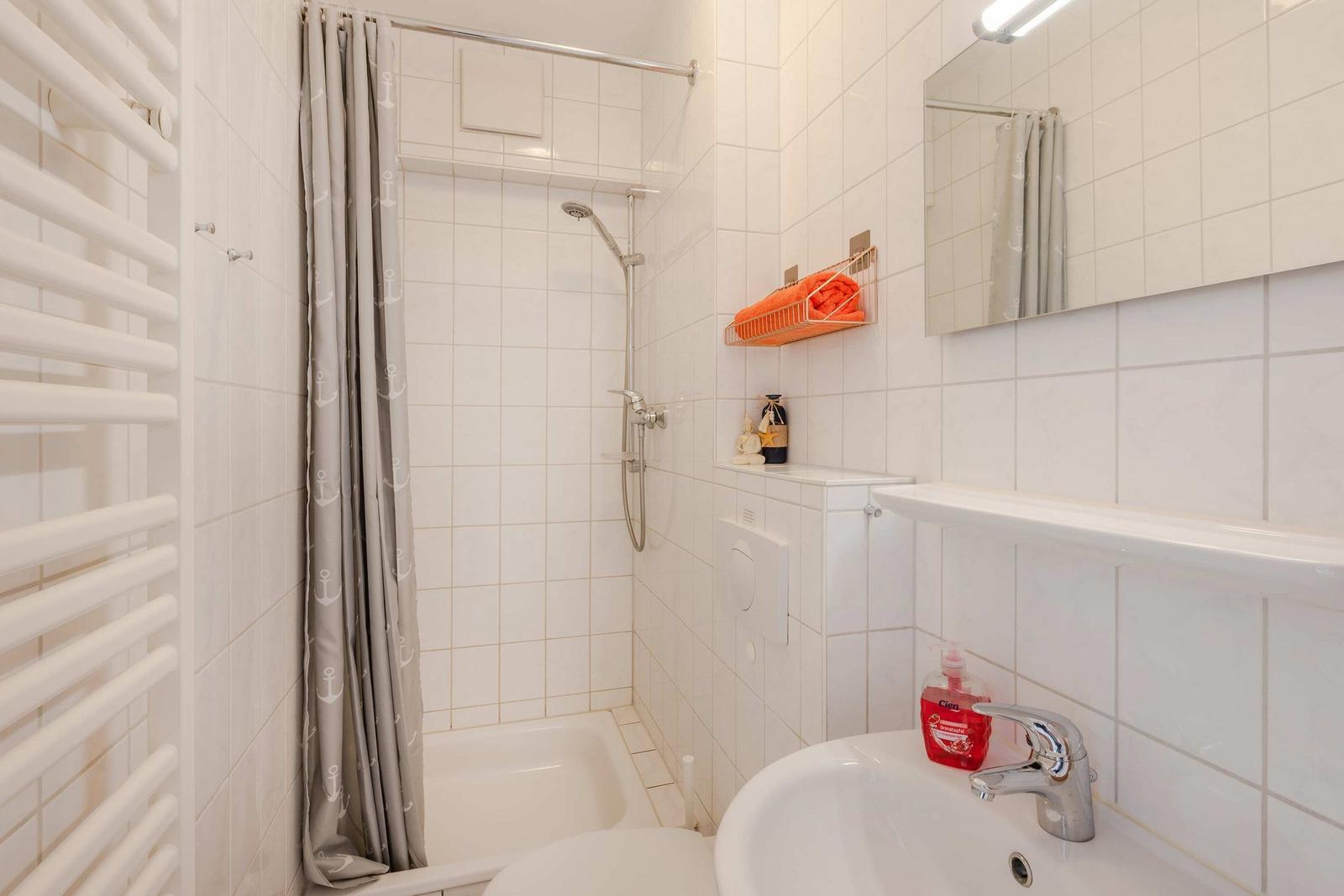 Badezimmer mit Dusche, Waschbecken und Handtuchhalter.