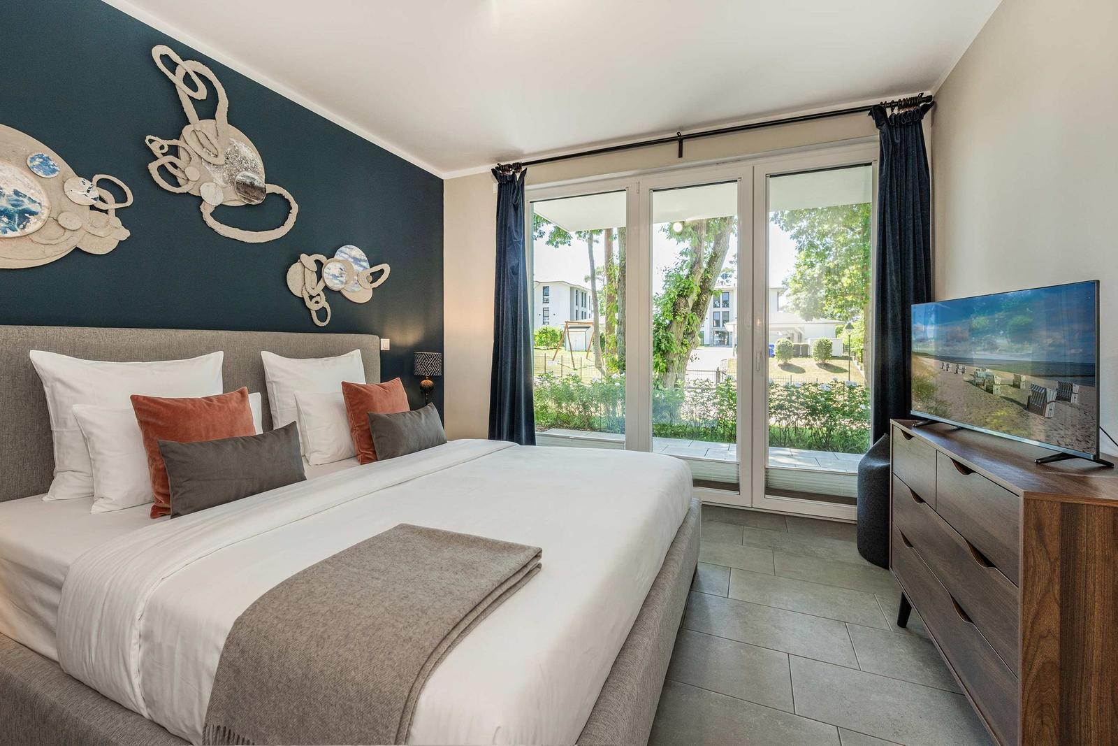 Schlafzimmer mit Bett, TV und Fenster zur Außenansicht.