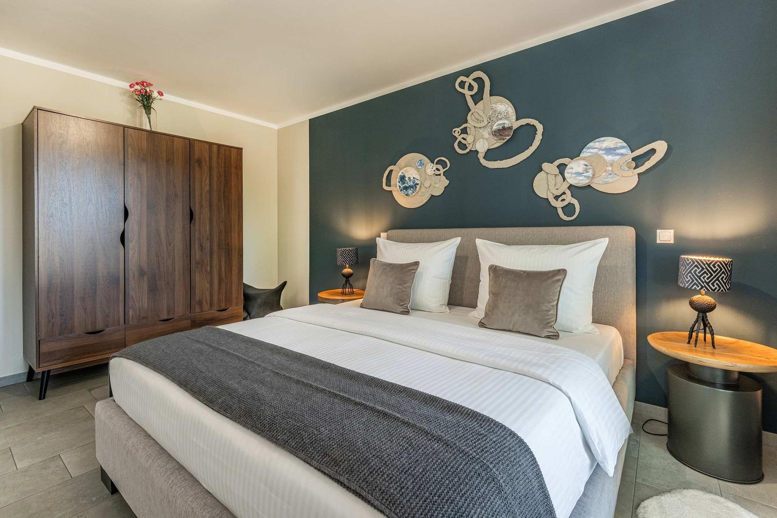 Schlafzimmer mit Bett, Nachttischen und Wanddekoration.