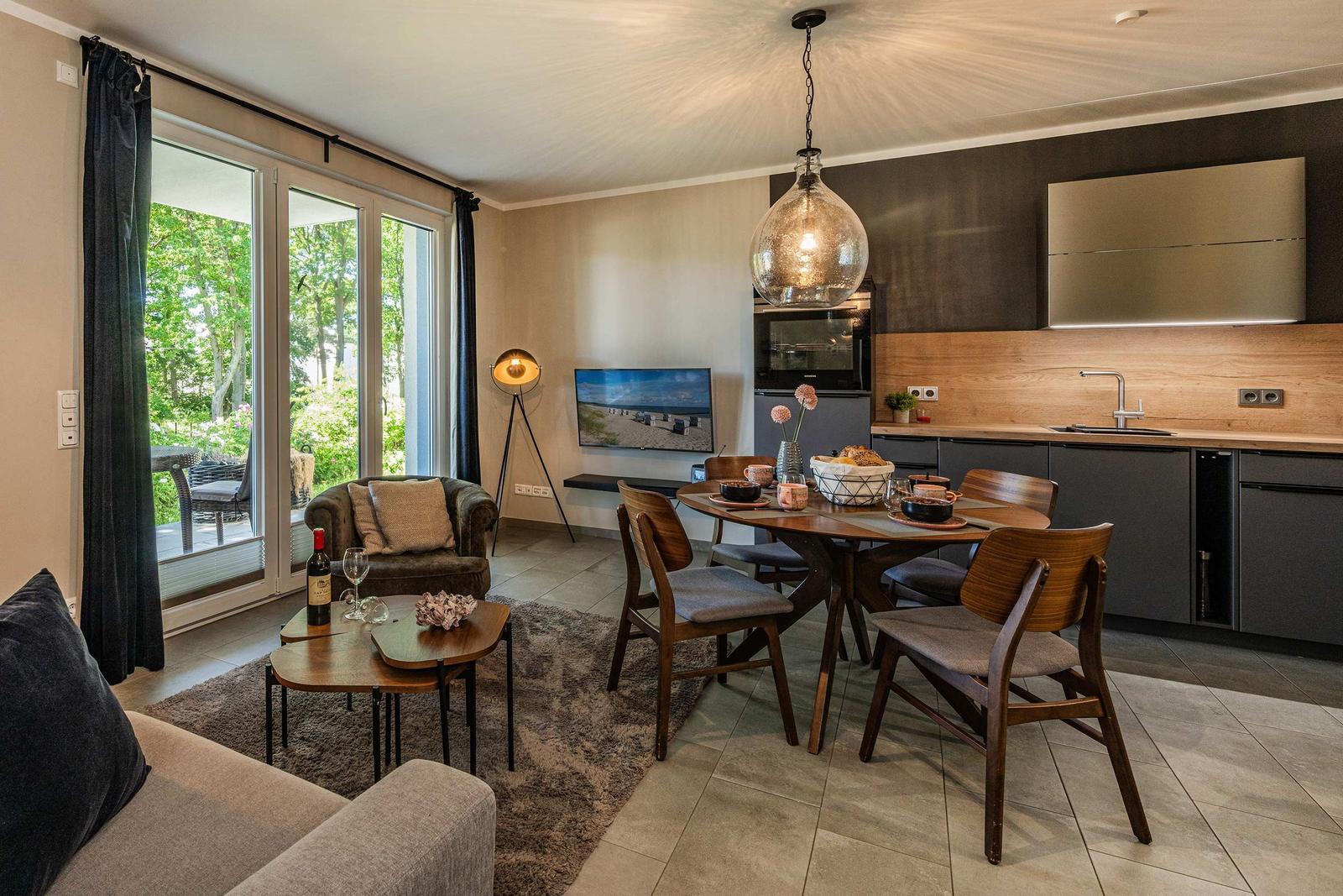 Wohn- und Essbereich mit Küchenzeile, Schlafzimmer und Terrasse mit Blick auf Grün.