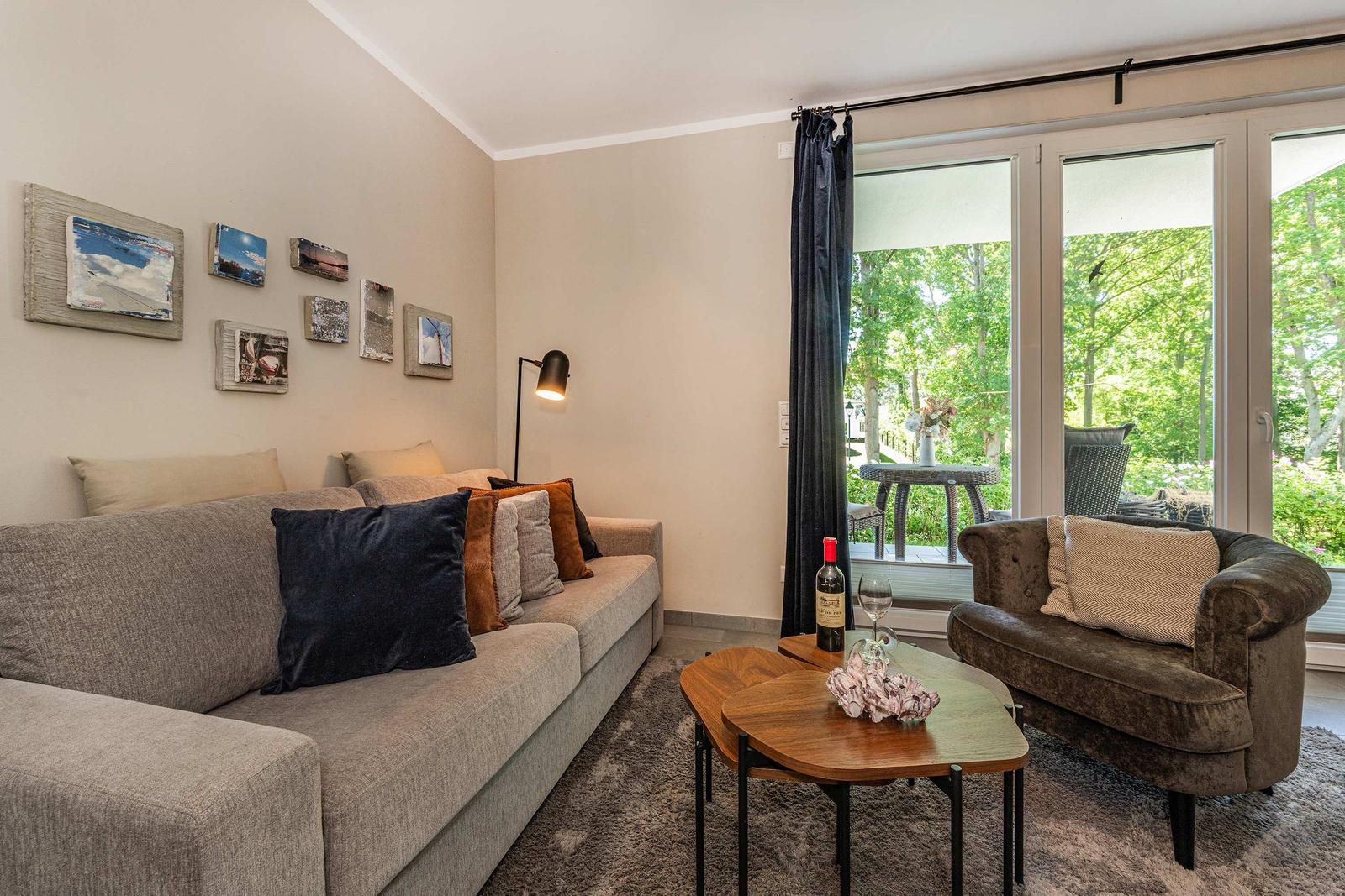 Wohnzimmer mit Sofa, Sessel und Blick auf Garten
