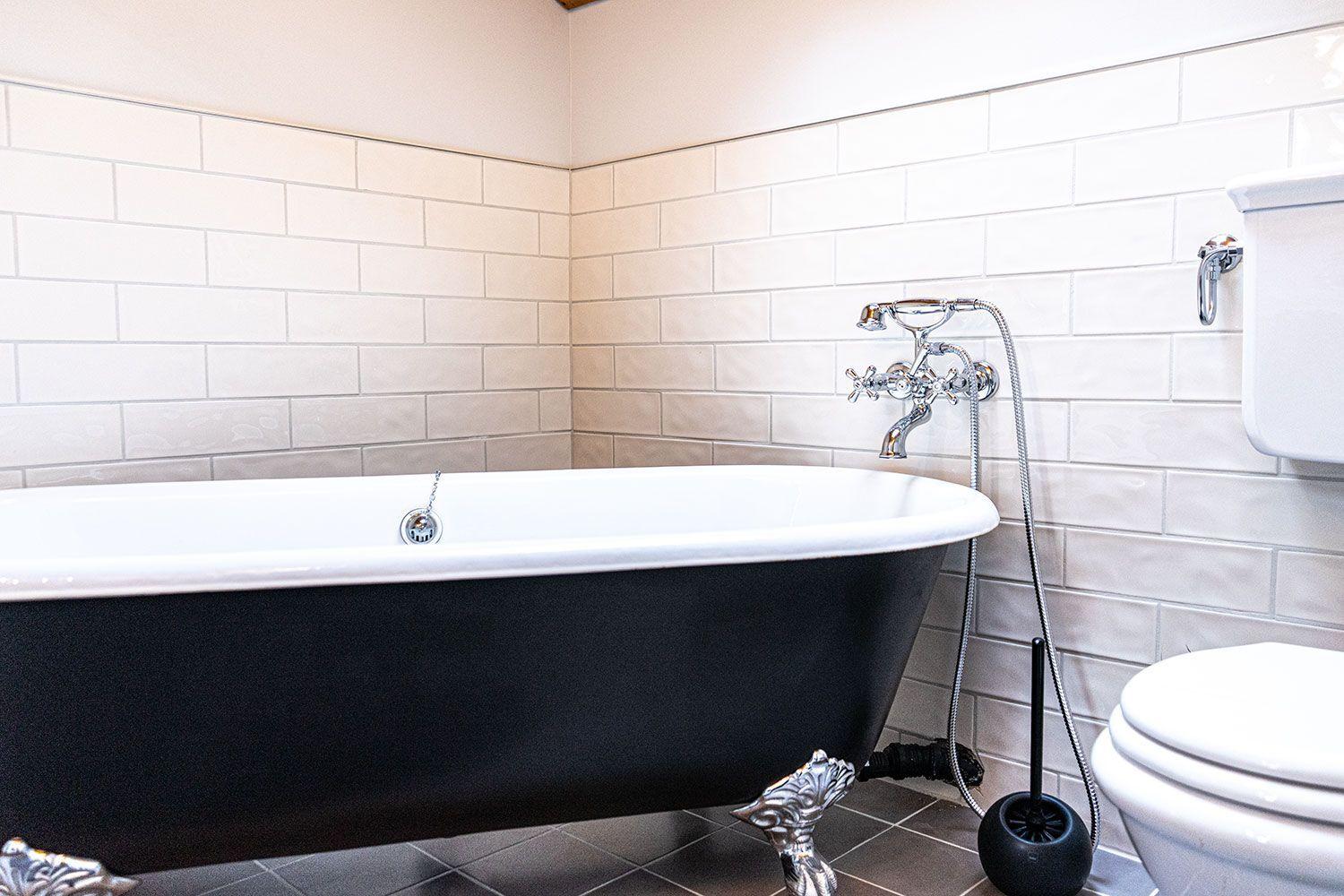 Bath with freestanding bathtub, toilet, and tiled wall.