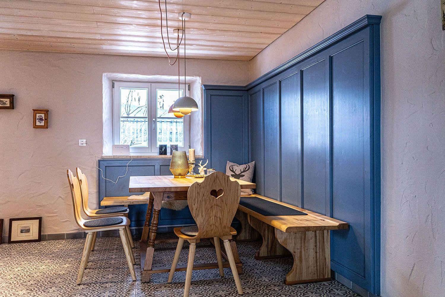 Dining room with wooden table, benches, and blue cabinets along the wall.