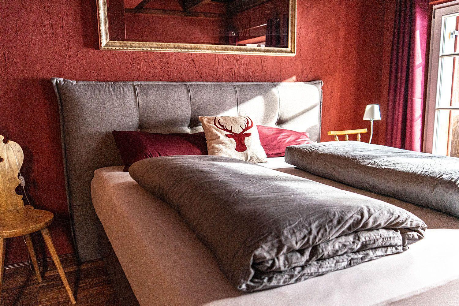 Bedroom with bed, pillows, and mirror on red wall.