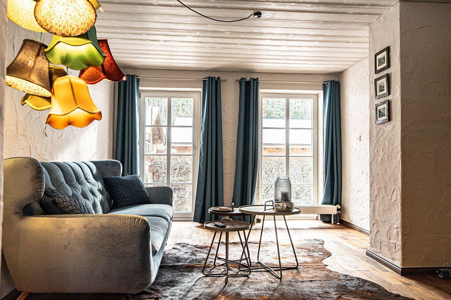 Living room with sofa, tables, and windows with curtains.
