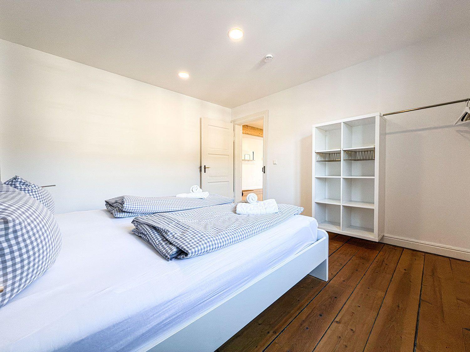 Bedroom with bed, wooden floor, and closet.