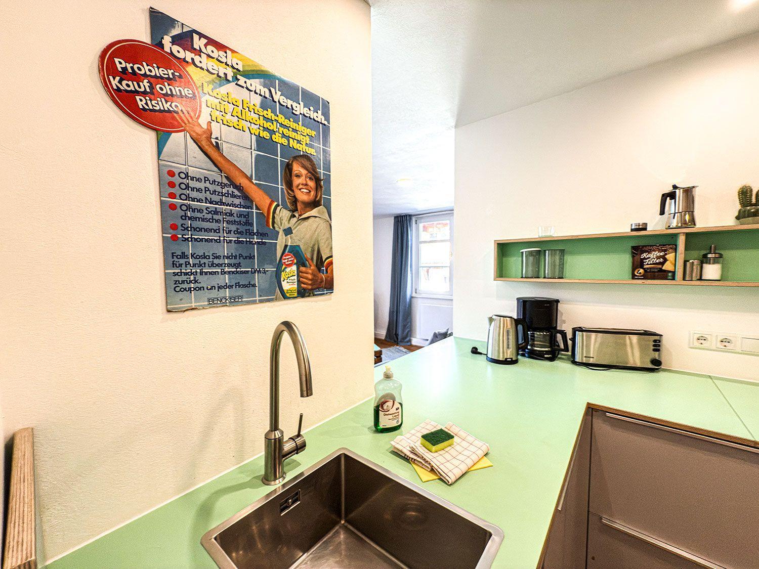 Kitchen with green countertop, sink, and appliances on the wall.