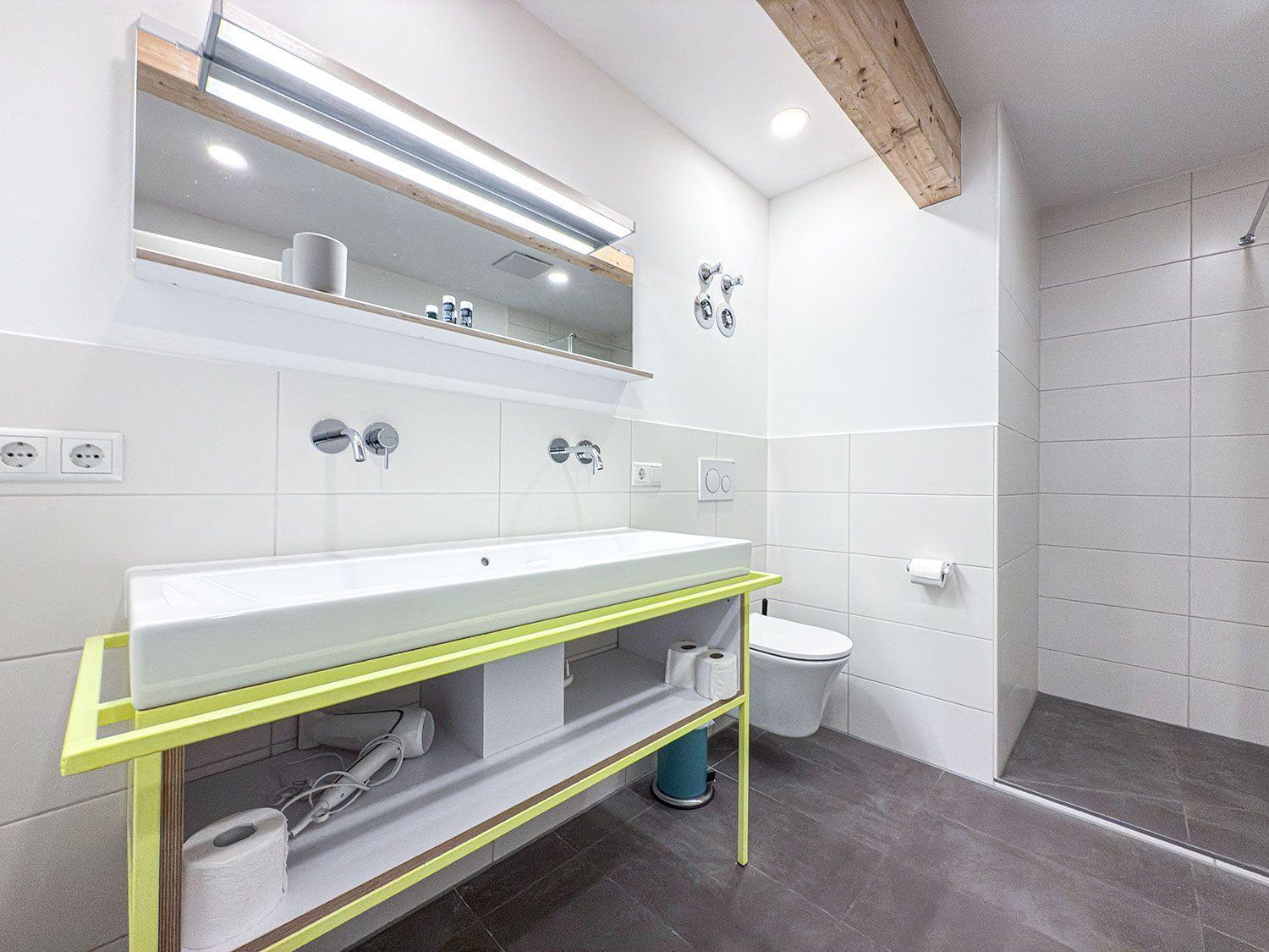 Bathroom with sink, toilet, and shower. Yellow base cabinet and mirror cabinet.
