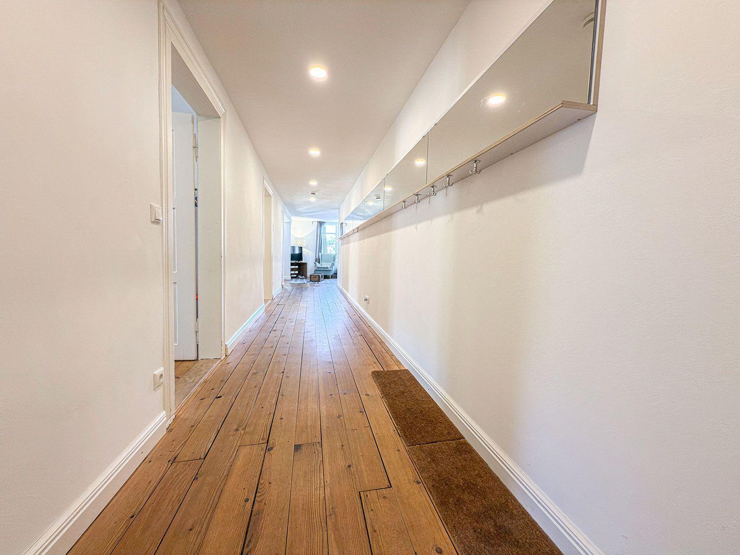 Langgang mit Holzboden und Spiegelschrank an der Wand.