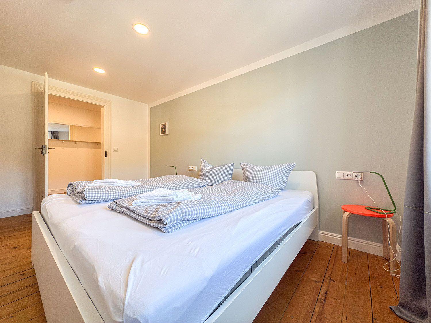 Schlafzimmer mit Bett, Kleiderschrank und Holzboden.