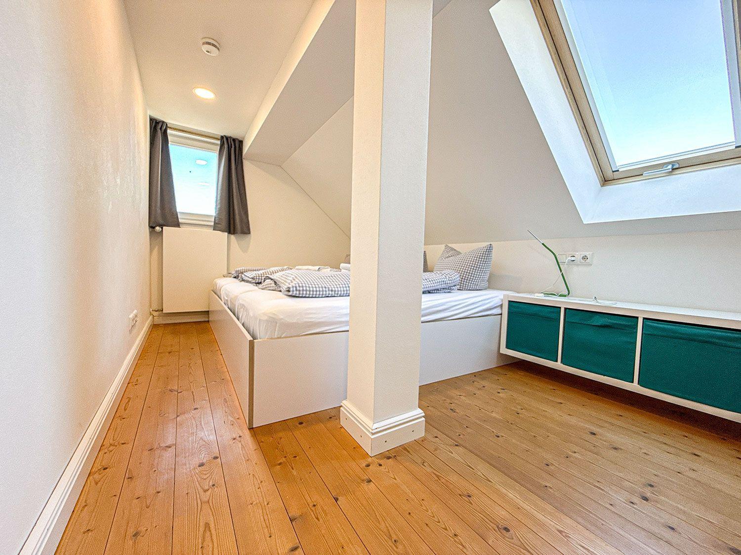 Schlafzimmer mit Dachfenster, Bett und Holzboden.