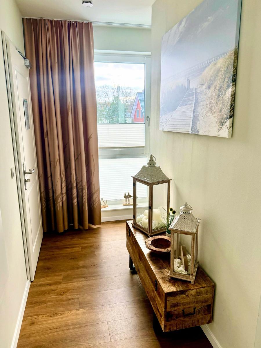 Eingangsbereich mit Holzboden, Vorhang, Fenster und Holzbank mit Laterne.
