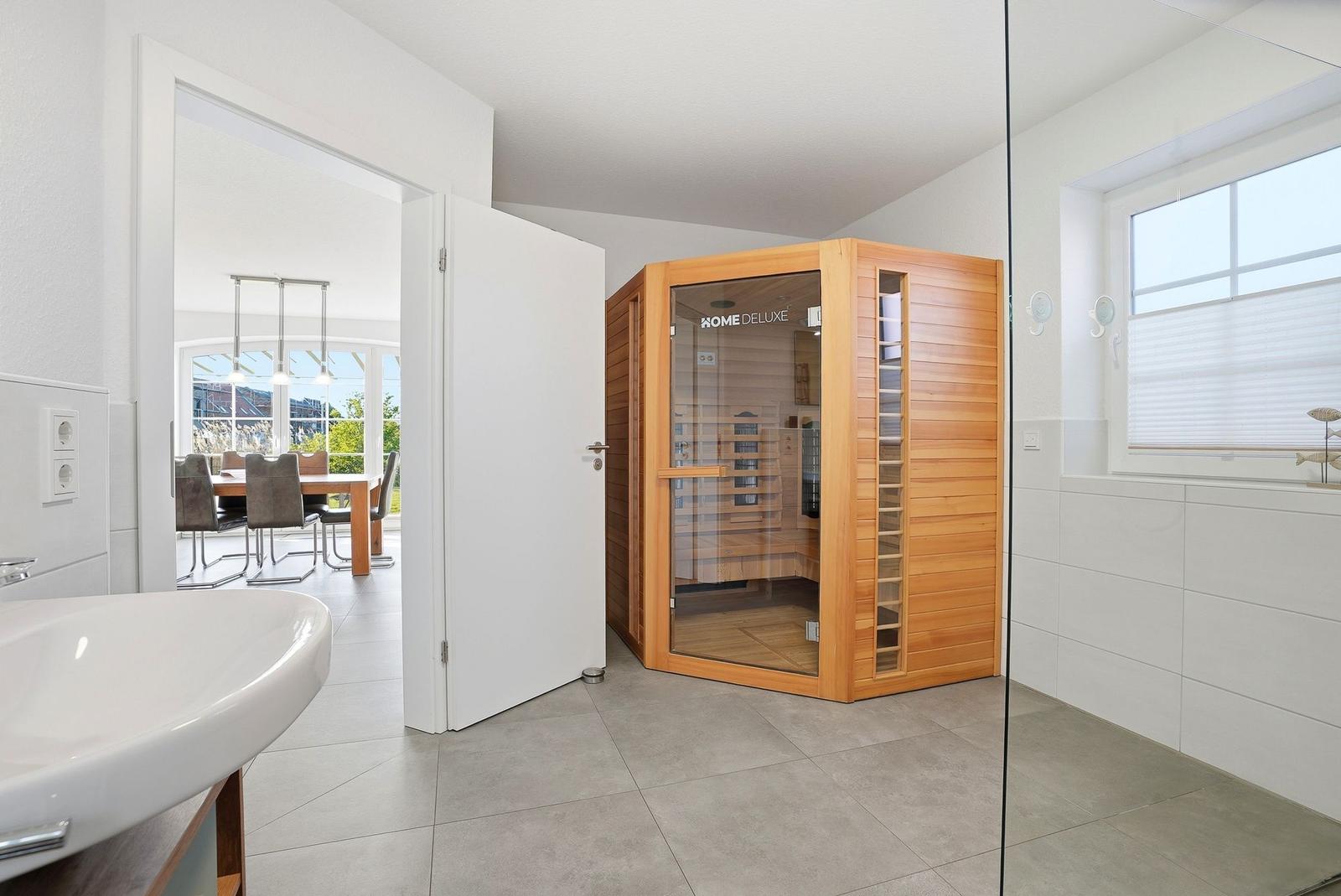 Eine Sauna mit Holzverkleidung und Glasfront in einem hellen Raum mit Fliesenboden.