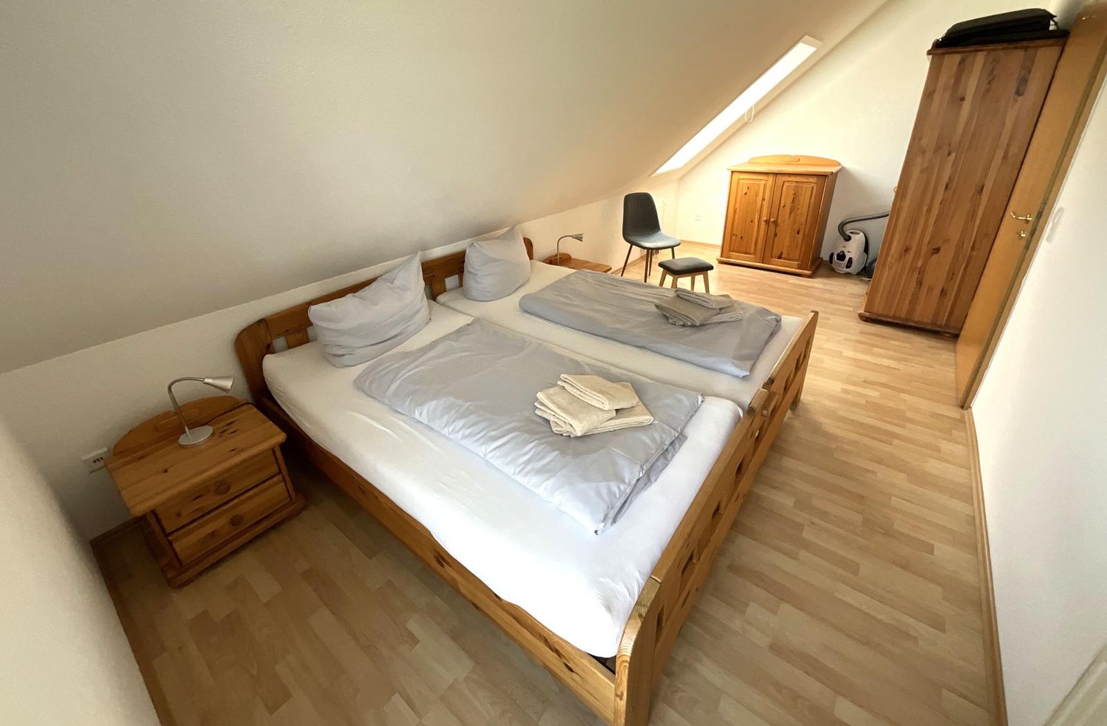 Schlafzimmer mit Doppelbett, Holzmöbel und Dachschrägen.