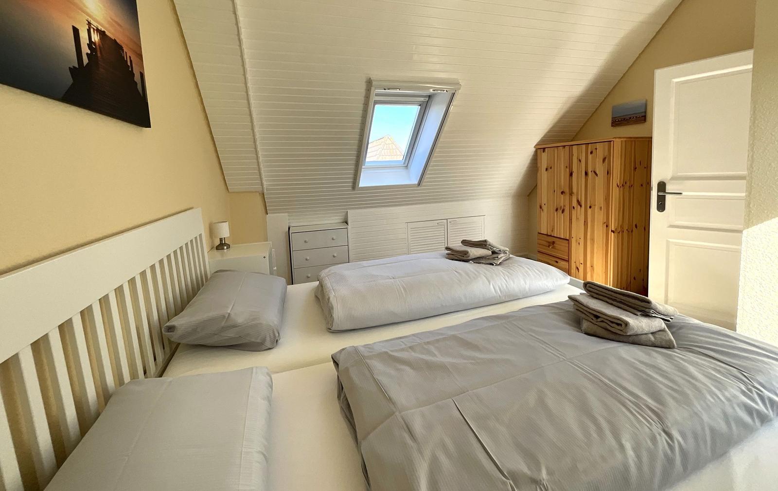 Schlafzimmer mit Dachschrägen, Dachfenster, Bett und Kleiderschrank.