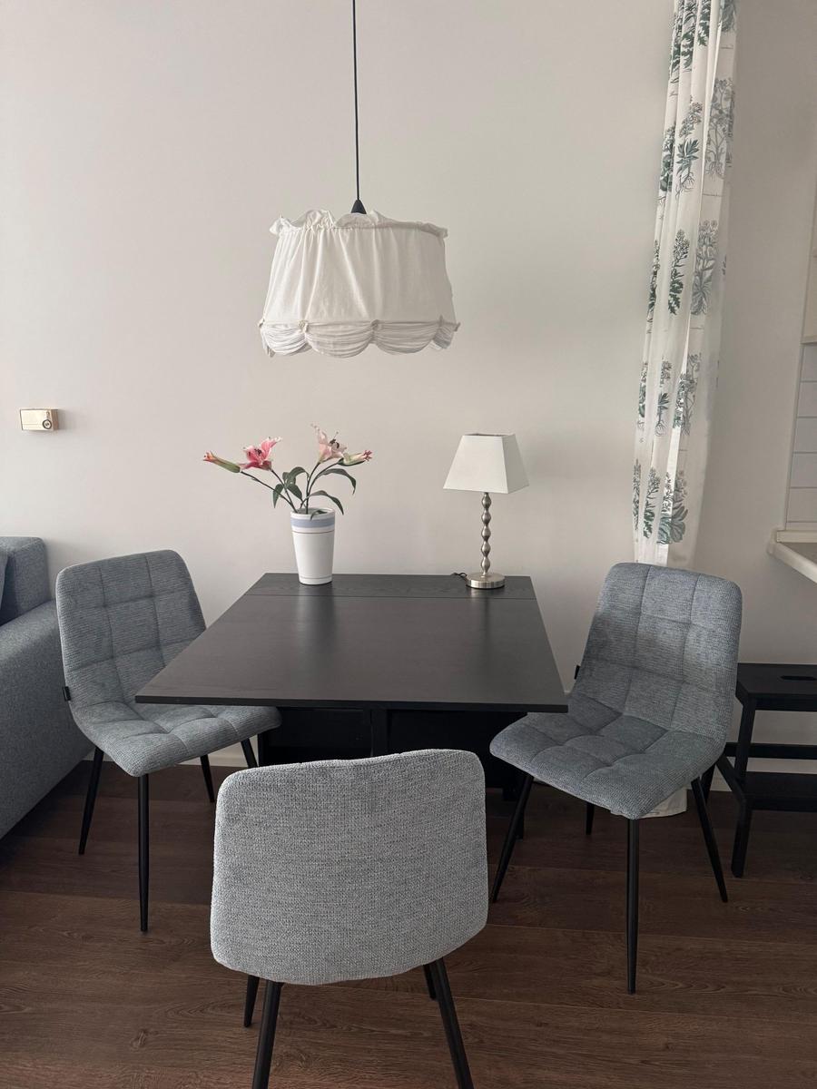 Dining table with three chairs, lamp, and flowers on the table.