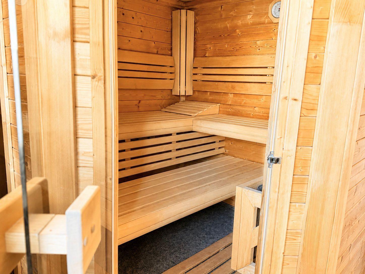 Holzsauna mit Sitzbänken und Temperaturmessgerät an der Wand.