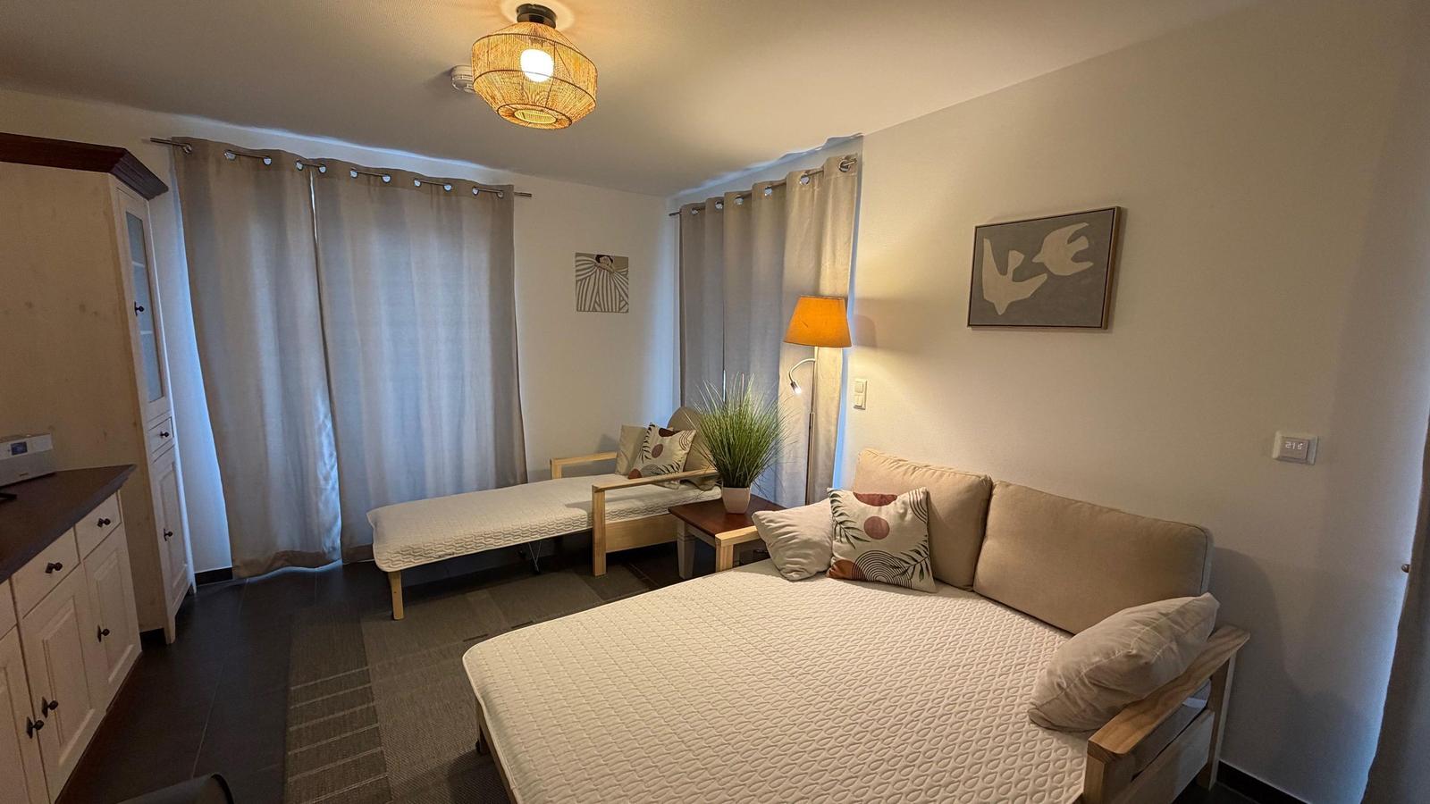 Ein Schlafzimmer mit Bett, Sofa, Lampe und Gardinen.
