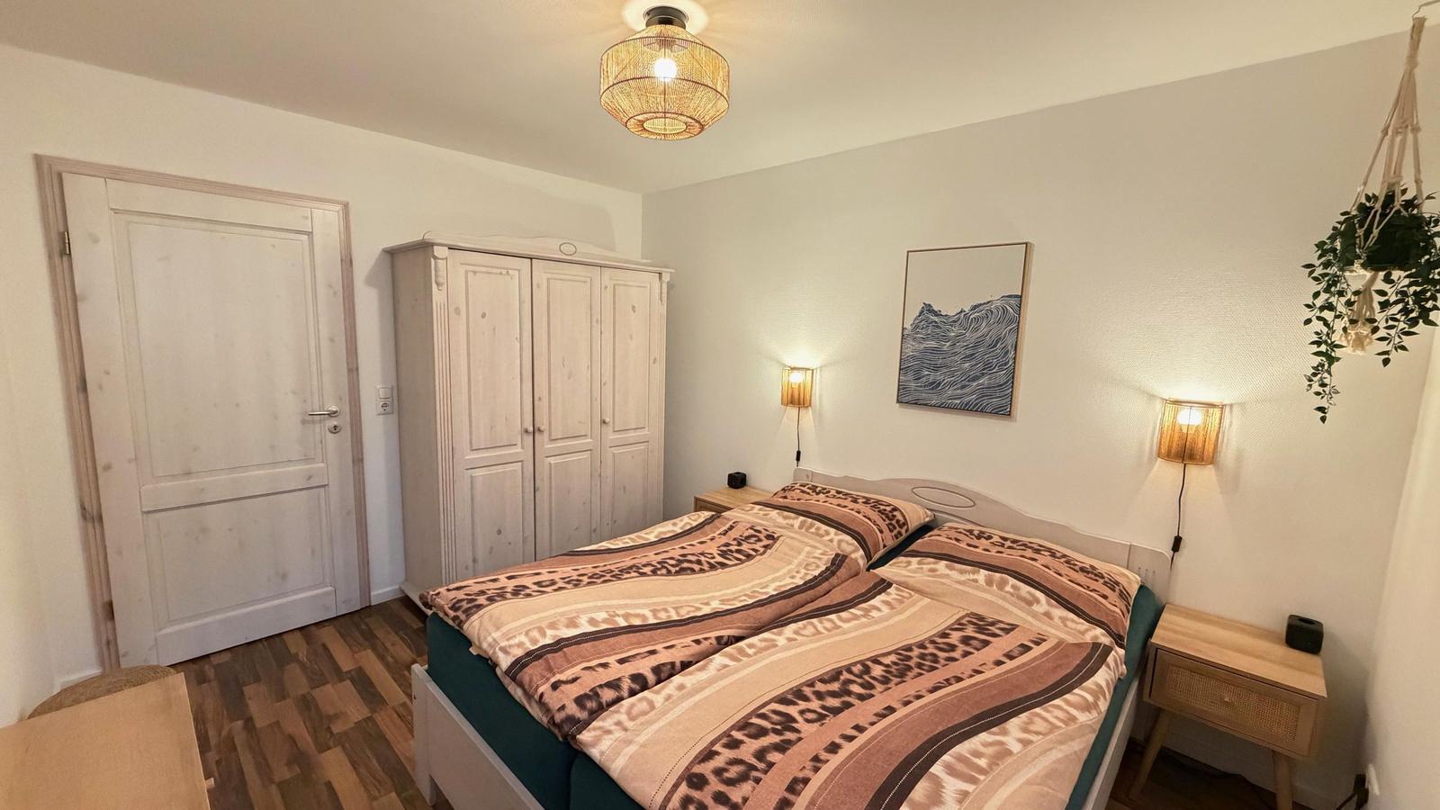 Schlafzimmer mit Doppelbett, Kleiderschrank und zwei Nachttischen mit Lampen.