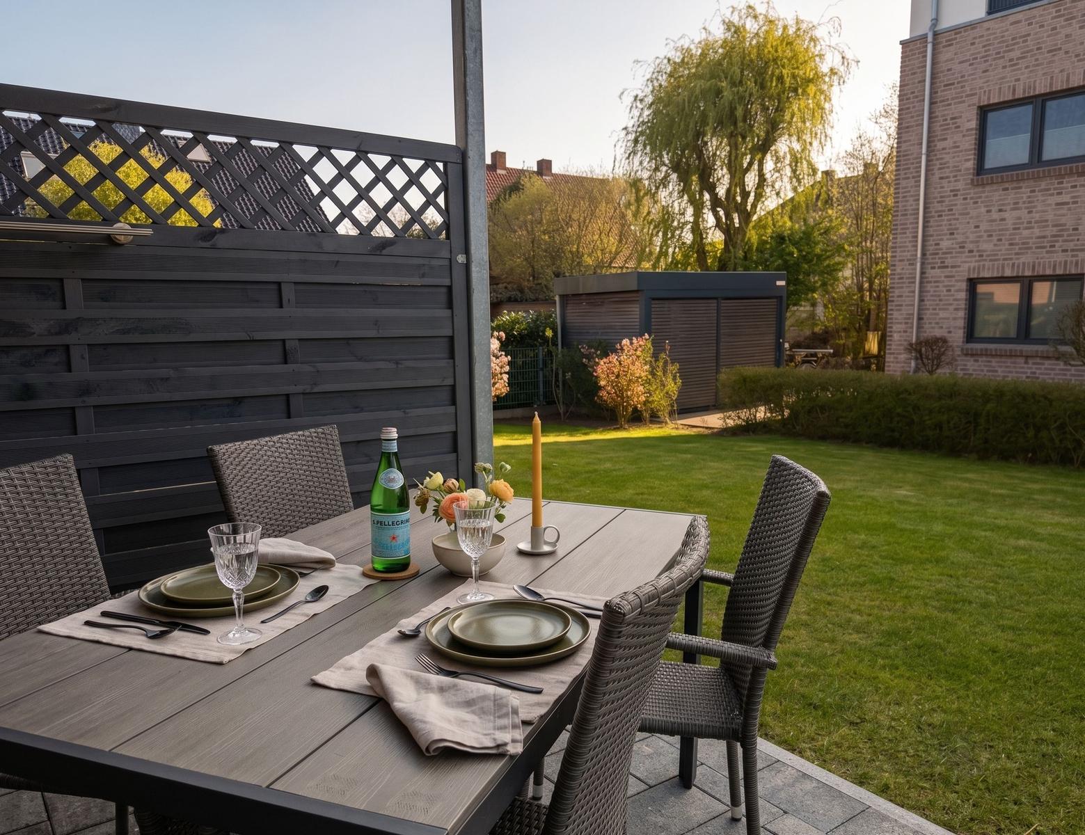 Garden with set table, green lawn, and wooden fence.
