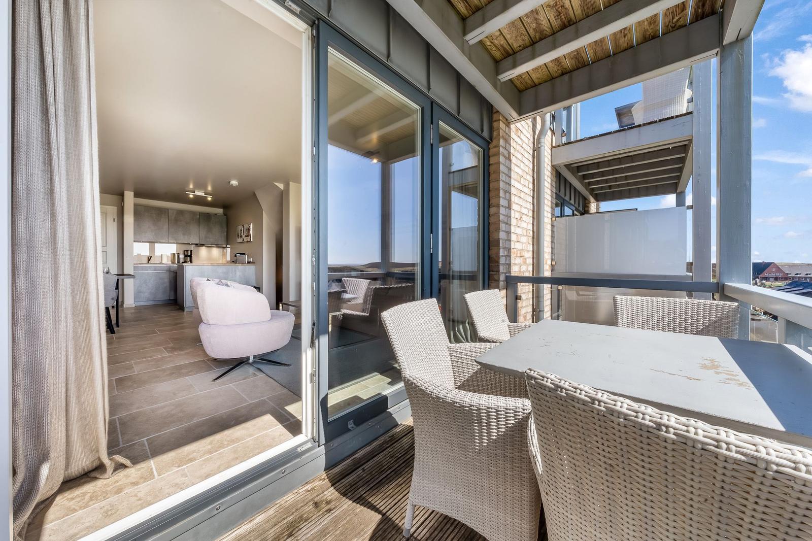 Terrasse mit Sitzgruppe und Blick in Wohnbereich mit Küche.