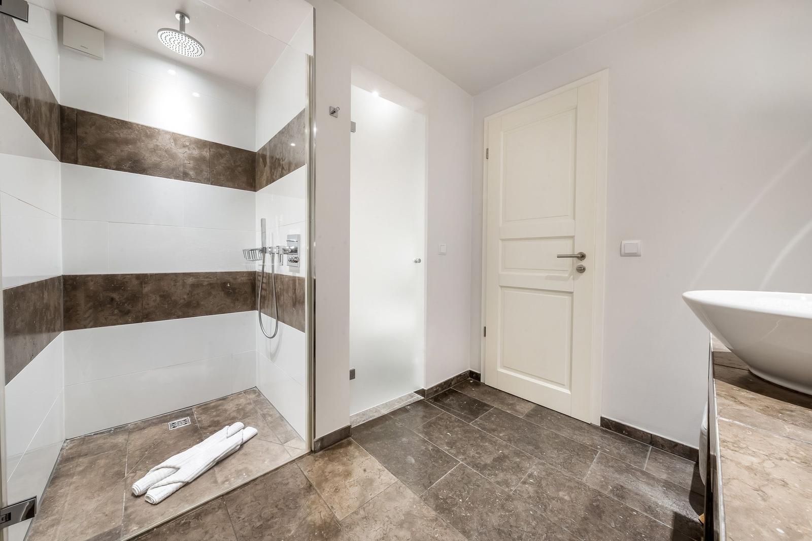 Dusche mit Regenduschkopf und Badewanne im modernen Badezimmer.
