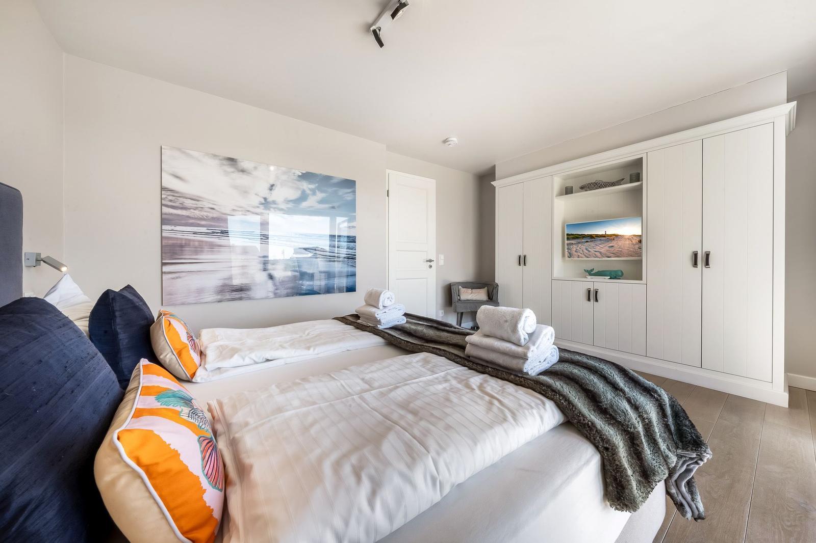 Schlafzimmer mit Bett, Kleiderschrank und Wandbild