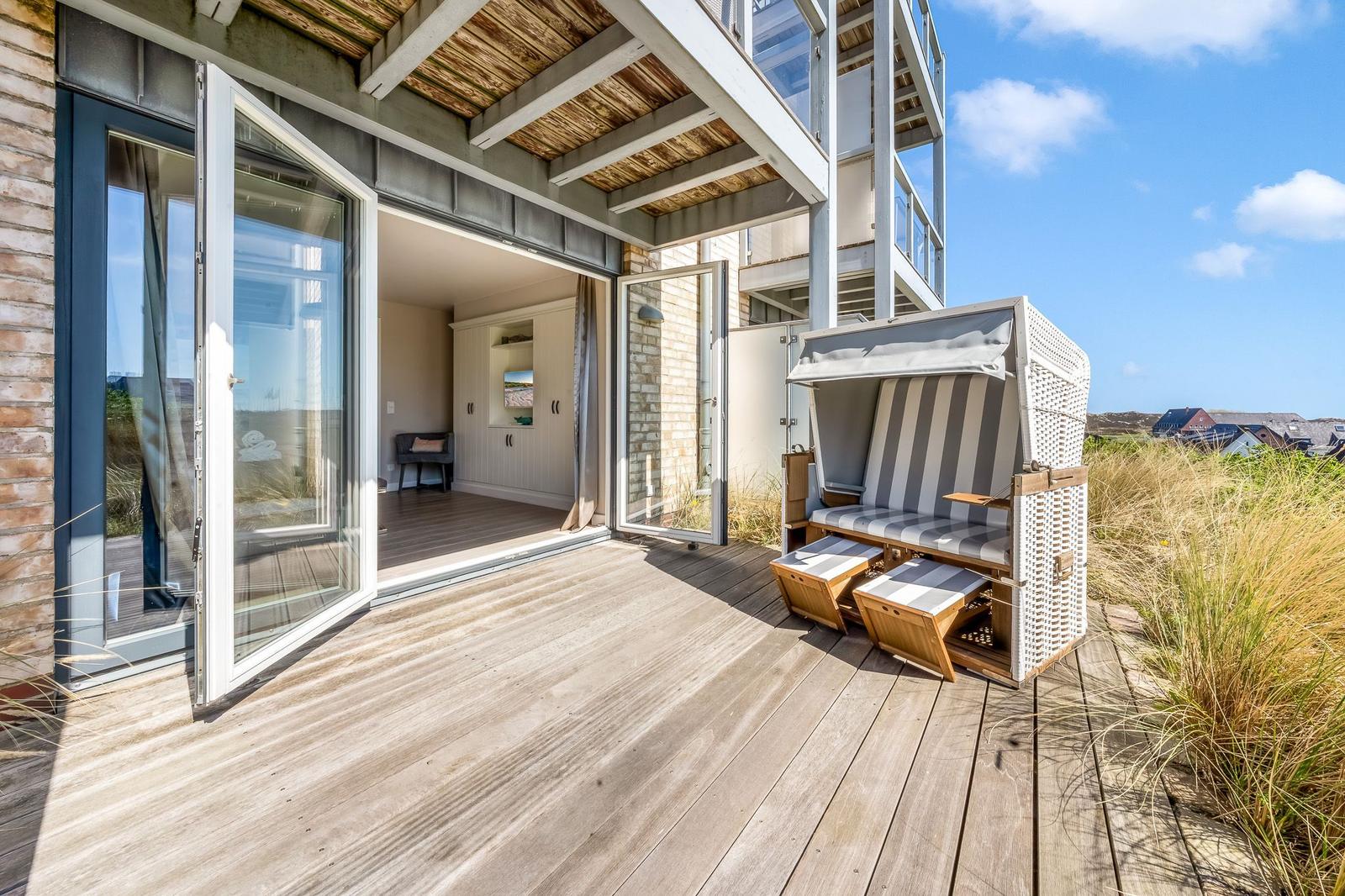 Terrasse mit Strandkorb und Blick auf die Dünen.
