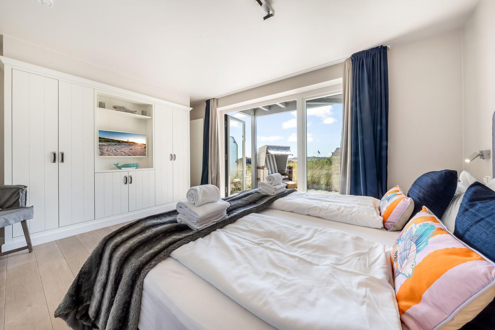 Schlafzimmer mit Blick auf die Strandpromenade und integriertem Fernseher.