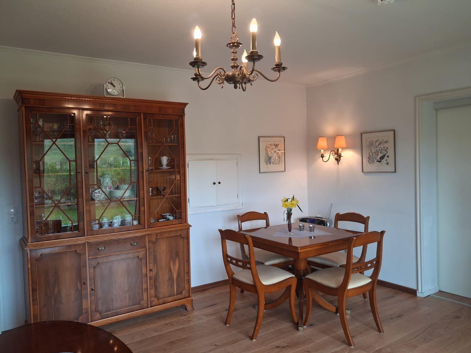 Dining room with wooden table, chairs, sideboard, and chandelier.