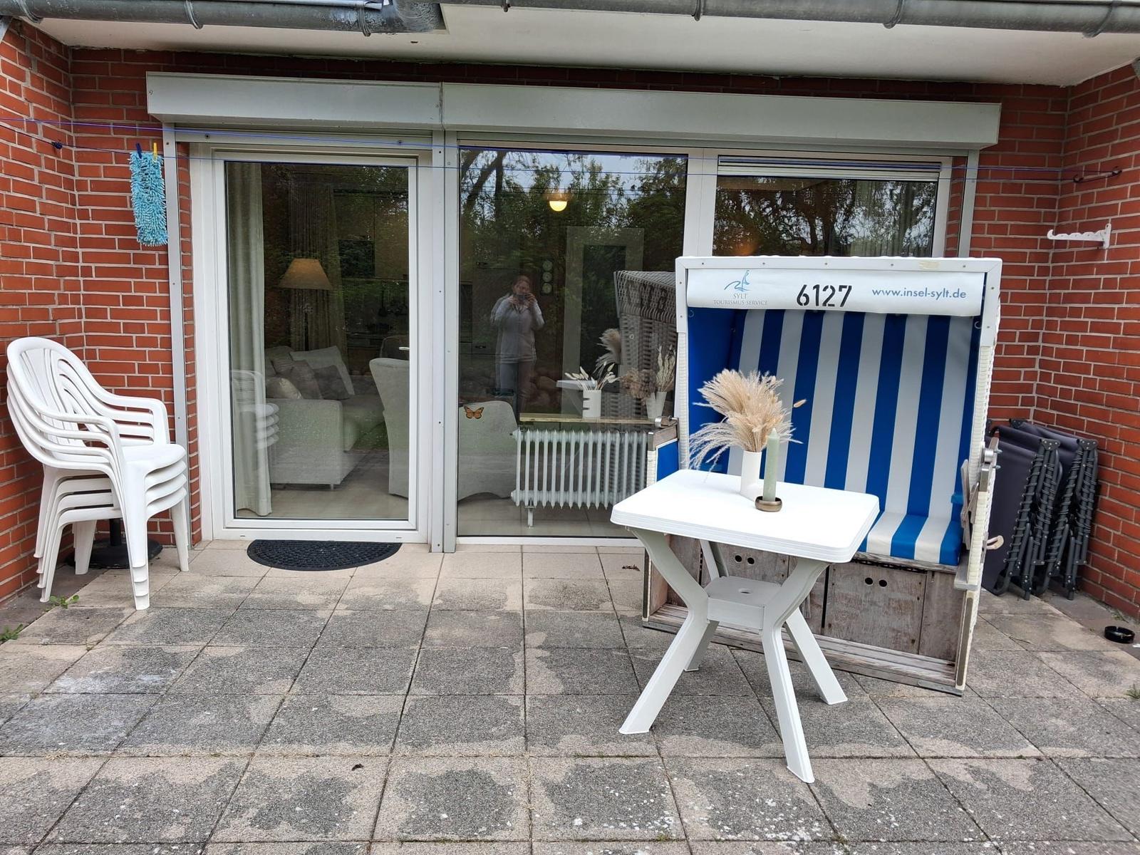 Terrasse mit Strandkorb, Tisch und Stühlen. Durchgang ins Wohnzimmer.