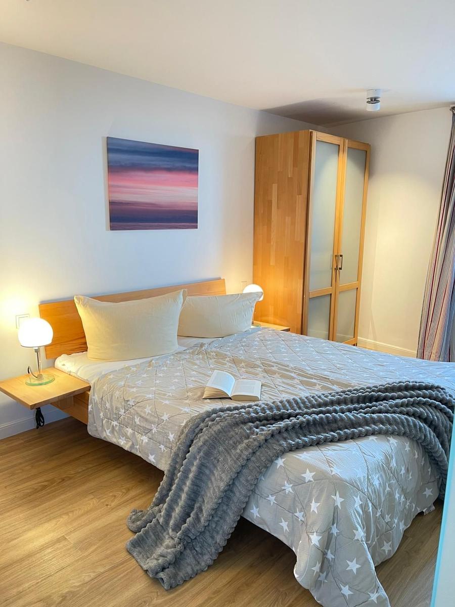 Schlafzimmer mit Bett, Nachttisch, Kleiderschrank und Wandbild.