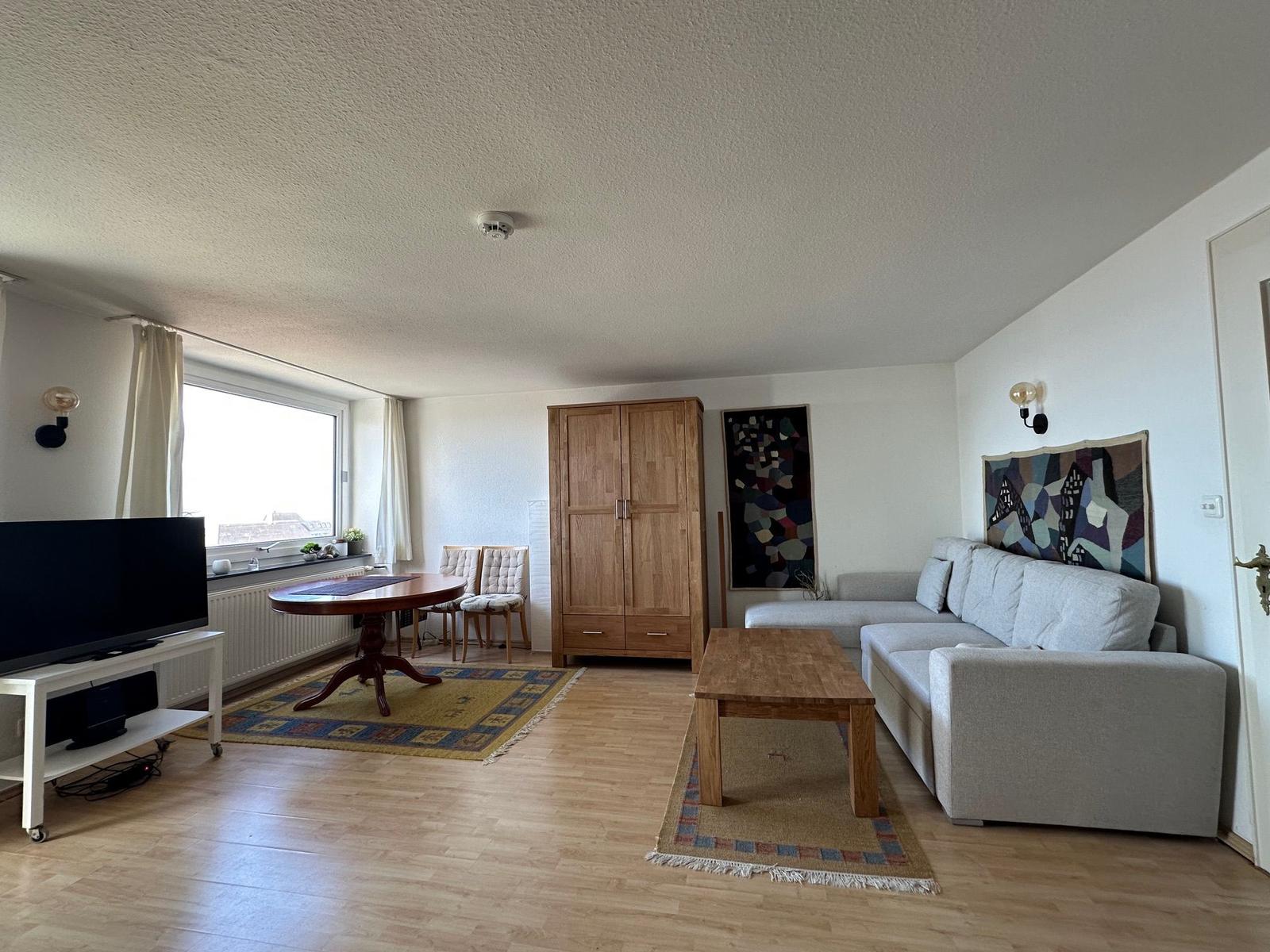 Wohnzimmer mit Sofa, Tisch, TV und Holzmöbel
