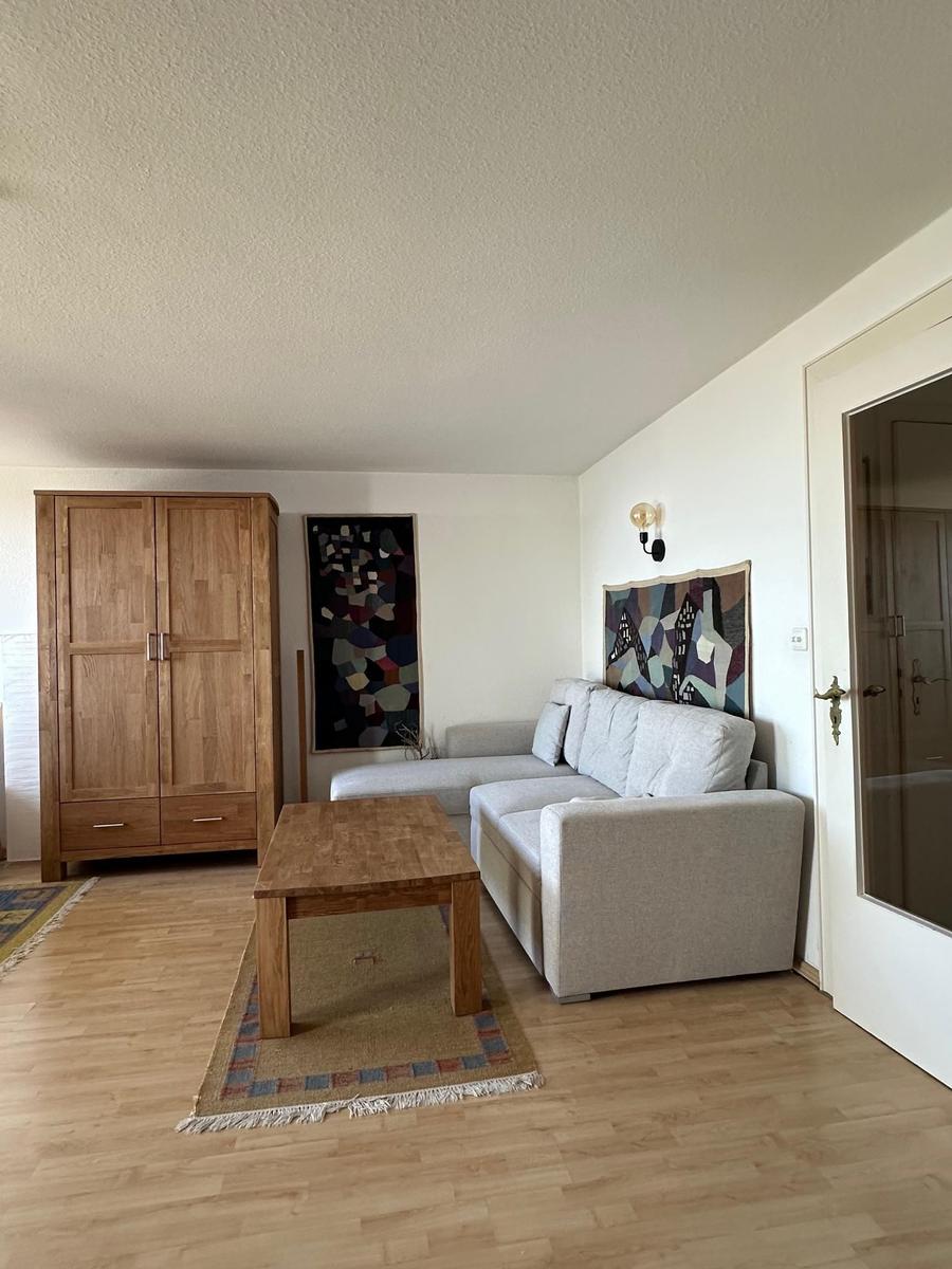 Wohnzimmer mit Sofa, Tisch und Kleiderschrank. Wandbild und Holzboden.