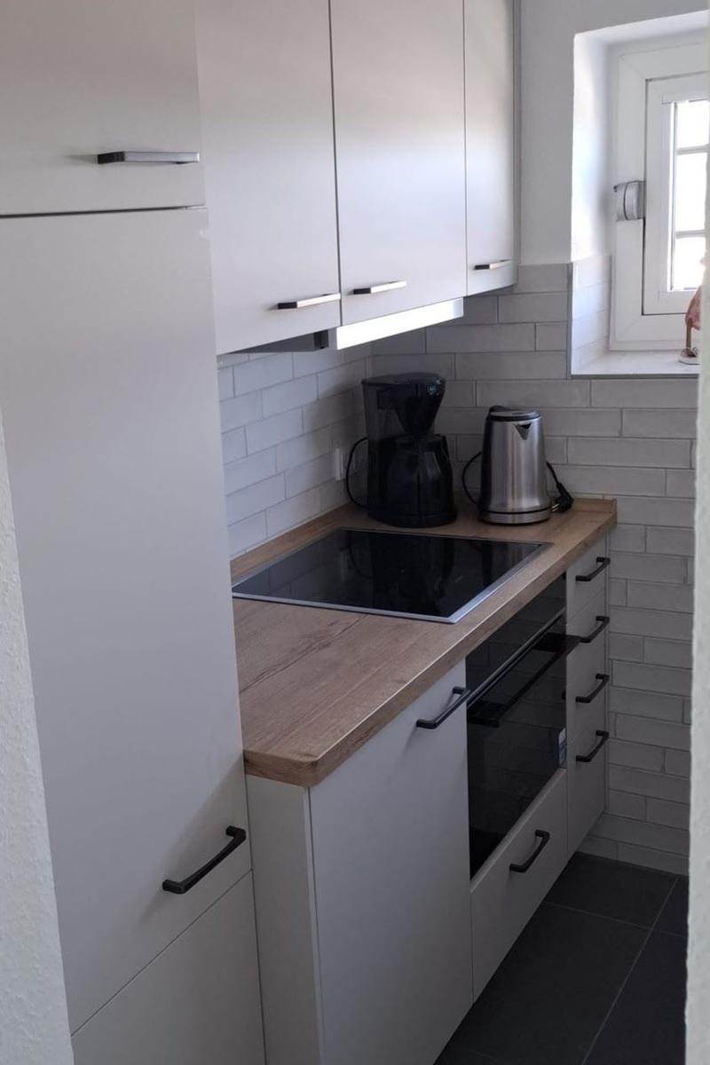 Küche mit weißen Schränken, Holzoberfläche und Induktionskochfeld.