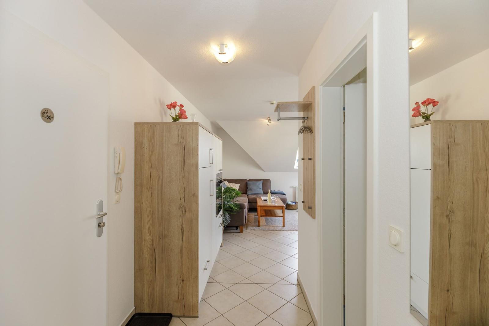 Flur mit Holzschrank und Blick in Wohnzimmer mit Sofa und Tisch